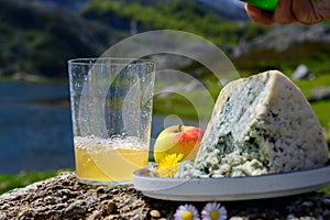 Glass of natural Asturian cider made fromÂ fermented apples, Asturian cabrales cow blue cheese with view on Covadonga lake and